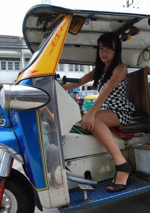 Inviting Thai adult model in a checkered dress gets into the Tuk Tuk Taxi