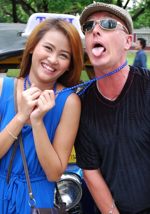 Hot dame from Thailand poses in her slinky blue dress by a small taxi