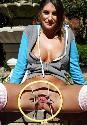 Sporty brunette with natural boobs stretches pussy outdoors with a special device