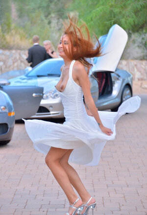 Playful minx poses on road in white dress that can barely cover her assets