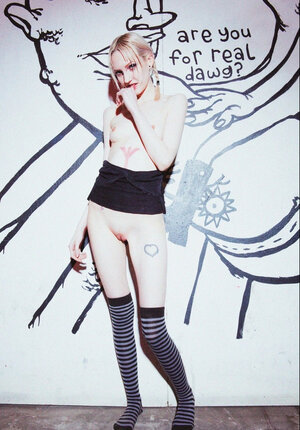 Small-tittied slim girl in striped over-the-knee socks poses by graffiti wall