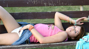 Attractive young girl flashes her white panties on the bench in the park