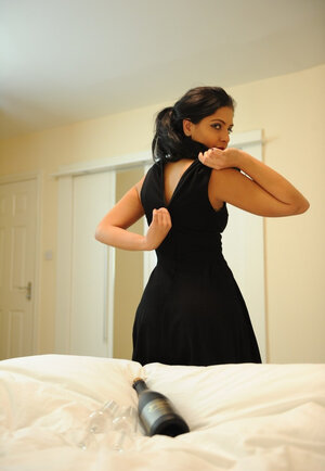 Nice-looking brunette takes off black dress and red lingerie posing naked on the bed